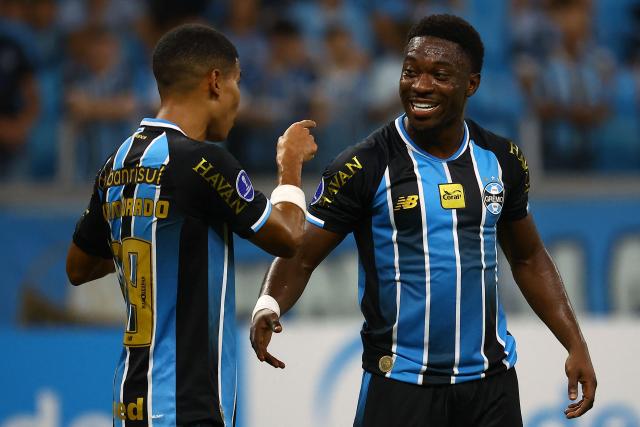 Gremio's Belgian midfielder #09 Francis Amuzu (R) celebrates with teammate Gremio's Colombian forward #99 Jose Enamorado after scoring his team's first goal during the Copa Sudamericana group stage football match between Brazil's Gremio and Argentina's Deportivo Riestra at the Arena do Gremio stadium in Porto Alegre, state of Rio Grande do Sul, Brazil, on April 14, 2026. (Photo by SILVIO AVILA / AFP)