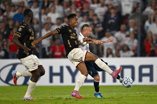 Nacional's midfielder #07 Nicolas Lopez scores his team's third goal next to Tolima's defender #03 Jan Carlos Angulo during the Copa Libertadores group stage football match between Uruguay's Nacional and Colombia's Deportes Tolima at the Gran Parque Central stadium in Montevideo on April 14, 2026. (Photo by Eitan ABRAMOVICH / AFP)