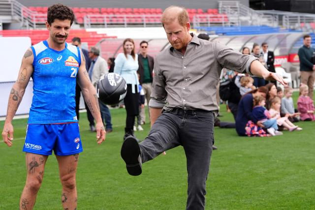 Britain's Prince Harry, Duke of Sussex (C), kicks a ball with Western Bulldogs Australian Football League (AFL) player Tom Liberatore (L) during a visit to a Movember event at Whitten Oval in Melbourne on April 15, 2026. (Photo by Jonathan Brady / POOL / AFP)