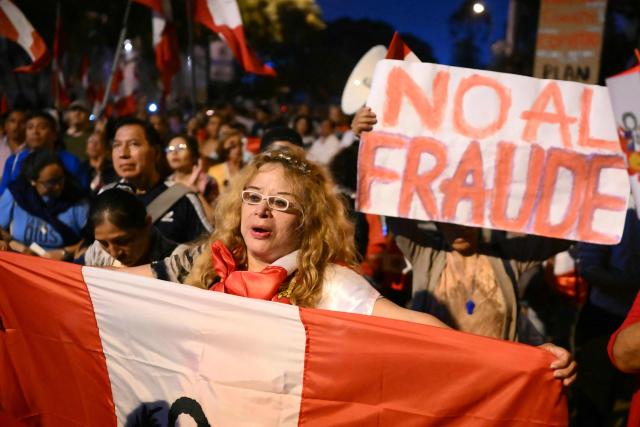 A demonstrator holds a national flag as she takes part in a protest over alleged fraud following the results of the presidential election in front of the National Jury of Elections (JNE) headquarters in Lima on April 14, 2026. Ultra-conservative candidate Rafael Lopez Aliaga, who is vying for a spot in the runoff of Peru’s presidential election, called on election authorities on April 14 to declare the election “null and void” due to unproven irregularities in the process. (Photo by Luis ROBAYO / AFP)