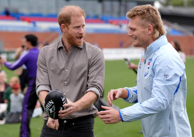 Britain's Prince Harry, Duke of Sussex (L), learns a hand-pass with Aussie Rules football with Western Bulldogs player Adam Treloar during a visit to a Movember event at Whitten Oval in Melbourne on April 15, 2026. (Photo by Jonathan Brady / POOL / AFP)