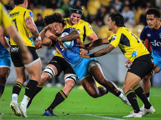 (FILES) A file photo taken on May 17, 2024 shows Danny Toala of Moana Pasifika (C) being tackled by Hurricanes' Justin Sangster during the Super Rugby match between the Wellington Hurricanes and Moana Pasifika at Sky Stadium in Wellington. Moana Pasifika confirmed on April 15, 2026 the Super Rugby franchise will fold at the end of the season, citing "financial, operational, and strategic realities". The team's 60 players and staff, led by coach Tana Umaga, were informed of the closure on April 14. (Photo by GRANT DOWN / AFP)