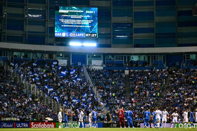 Players wait on the pitch as the CONCACAF Champions Cup quarterfinal football match between Mexico's Cruz Azul and US' Los AngelesFC (LAFC) was detained due to discriminatory chants at Cuauhtemoc stadium in Puebla, Mexico on April 14, 2026. (Photo by Yuri CORTEZ / AFP)
