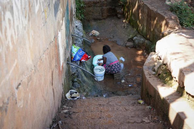 (FILES) A woman washes clothes at a public fountain distributing non-drinkable water in Cavani district, in the township of Mamoudzou, on the French Indian Ocean territory of Mayotte, on October 31, 2025. For three years now, the taps in Mayotte have been running only intermittently. As the Paris criminal court delivers its ruling on April 16, 2026 in the trial of the former management of the water authority, the people of Mayotte are enduring scheduled water cuts, the legacy of a historic drought in 2023, but also of poor management and exhausted infrastructure. (Photo by Marine GACHET / AFP)