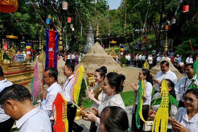 People walk around sand stupas as they pray during celebrations for the Khmer New Year, known as Nokor Sankranta, in Phnom Penh on April 15, 2026. (Photo by TANG CHHIN Sothy / AFP)
