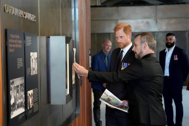 Britain's Prince Harry, the Duke of Sussex (C), inspects the Captain Reg Saunders wall during a visit to the Australian War Memorial in Canberra on April 15, 2026. (Photo by Jonathan Brady / POOL / AFP)