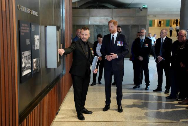 Britain's Prince Harry, the Duke of Sussex (C), inspects the Captain Reg Saunders wall during a visit to the Australian War Memorial in Canberra on April 15, 2026. (Photo by Jonathan Brady / POOL / AFP)