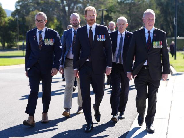 Britain's Prince Harry, the Duke of Sussex (C), walks with Lieutenant Colonel Joseph West (L), memorial representatives and Indigenous veterans during a visit to the Australian War Memorial in Canberra on April 15, 2026. (Photo by Jonathan Brady / POOL / AFP)