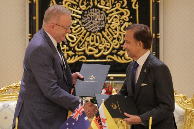 Brunei's Sultan Hassanal Bolkiah (R) and Australia's Prime Minister Anthony Albanese (L) exchange documents after a signing ceremony at Istana Nurul Iman in Bandar Seri Begawan on April 15, 2026. Albanese is travelling to Brunei and Malaysia to discuss energy and food security, his office said on April 12, continuing regional efforts to shore up fuel supplies for a nation reliant on imports. (Photo by Muhammad Rudean / AFP)