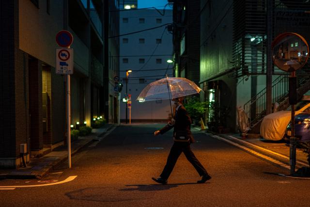 A man holding an umbrella walks along a street in Tokyo's Asakusabashi district on April 15, 2026. (Photo by Philip FONG / AFP)