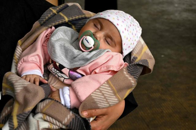 A displaced woman carries her baby at a corridor in a school transformed into a displaced reception center in the area of Dekwaneh, east of Beirut on April 15, 2026. United Nations refugee chief Barham Salih on April 15 called on the international community to provide urgent support to Lebanon, with a fifth of the country's population displaced by the Israel-Hezbollah war. (Photo by Joseph EID / AFP)