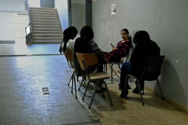 Displaced women smoke waterpipe at a corridor at a corridor in a school transformed into a displaced reception center in the area of Dekwaneh, east of Beirut on April 15, 2026. United Nations refugee chief Barham Salih on April 15 called on the international community to provide urgent support to Lebanon, with a fifth of the country's population displaced by the Israel-Hezbollah war. (Photo by Joseph EID / AFP)