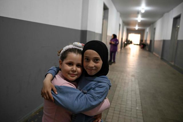 Displaced girls embrace eachother as they pose for a picture in a school transformed into a displaced reception center in the area of Dekwaneh, east of Beirut on April 15, 2026. United Nations refugee chief Barham Salih on April 15 called on the international community to provide urgent support to Lebanon, with a fifth of the country's population displaced by the Israel-Hezbollah war. (Photo by Joseph EID / AFP)