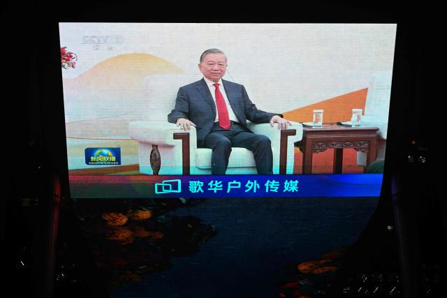 News footage on a giant screen outside a shopping mall in Beijing shows General Secretary of the Communist Party of Vietnam and Vietnam's President To Lam attending an event with China's President Xi Jinping on April 15, 2026. (Photo by Pedro PARDO / AFP)