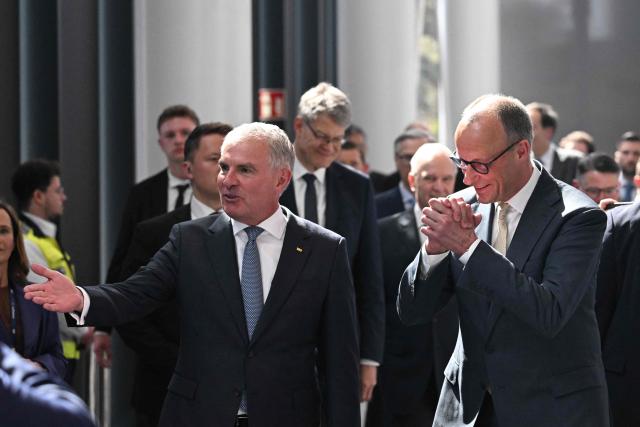 Lufthansa CEO Carsten Spohr welcomes German Chancellor Friedrich Merz (R) during a ceremony to celebrate the 100th anniversary of the founding of the first Lufthansa at Lufthansa Group Hangar One, Frankfurt Aiport, in Frankfurt am Main, western Germany on April 15, 2026. In 1926, the "Deutsche Luft Hansa Aktiengesellschaft" (renamed "Lufthansa" in 1933), was formed from a merger between "Deutsche Aero Lloyd" (DAL) and "Junkers Luftverkehr". (Photo by Kirill KUDRYAVTSEV / AFP)