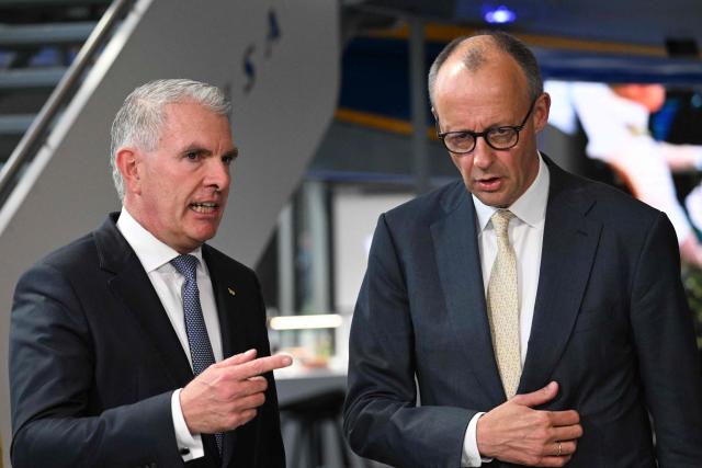 German Chancellor Friedrich Merz (R) talk to Lufthansa CEO Carsten Spohr during a ceremony to celebrate the 100th anniversary of the founding of the first Lufthansa at Lufthansa Group Hangar One, Frankfurt Aiport, in Frankfurt am Main, western Germany on April 15, 2026. In 1926, the "Deutsche Luft Hansa Aktiengesellschaft" (renamed "Lufthansa" in 1933), was formed from a merger between "Deutsche Aero Lloyd" (DAL) and "Junkers Luftverkehr". (Photo by Kirill KUDRYAVTSEV / AFP)