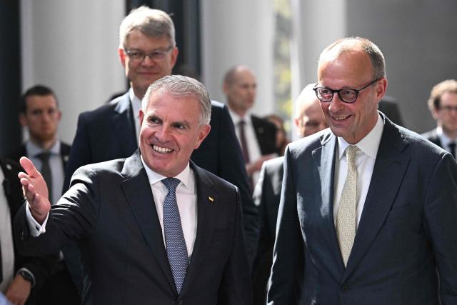 Lufthansa CEO Carsten Spohr welcomes German Chancellor Friedrich Merz (R) during a ceremony to celebrate the 100th anniversary of the founding of the first Lufthansa at Lufthansa Group Hangar One, Frankfurt Aiport, in Frankfurt am Main, western Germany on April 15, 2026. In 1926, the "Deutsche Luft Hansa Aktiengesellschaft" (renamed "Lufthansa" in 1933), was formed from a merger between "Deutsche Aero Lloyd" (DAL) and "Junkers Luftverkehr". (Photo by Kirill KUDRYAVTSEV / AFP)