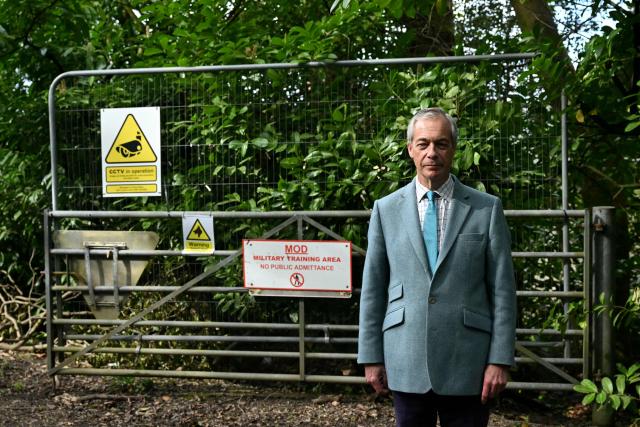 Reform UK party leader Nigel Farage poses for a photo outside the entrance to Crowborough military barracks which houses illegal migrants, during his walkabout to campaign in the town of Crowborough, south-east England on April 15, 2026, ahead of local elections on May 7. (Photo by JUSTIN TALLIS / AFP)