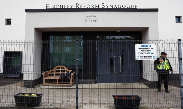 A security guard stands on duty outside Finchley Reform Synagogue, in the North Finchley area of north London, on April 15, 2026, following an attack on the synagogue in the early hours of the morning. Britain's Metropolitan Police said on April 15 they are seeking two suspects following an attempted arson attack at Finchley Reform Synagogue in north London, where bottles thought to have  contained petrol were thrown at the building. (Photo by Toby Shepheard / AFP)