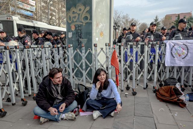 Members of education unions sit in front of a police barricade to protest school shootings, next to the Ministry of National Education headquarters in Ankara, on April 15, 2026. A 13-year-old opened fire at a Turkish school on April 15, 2026, killing nine people and wounding 13, with students jumping from windows to escape the second school shooting in the country in as many days, officials said. (Photo by Adem ALTAN / AFP)