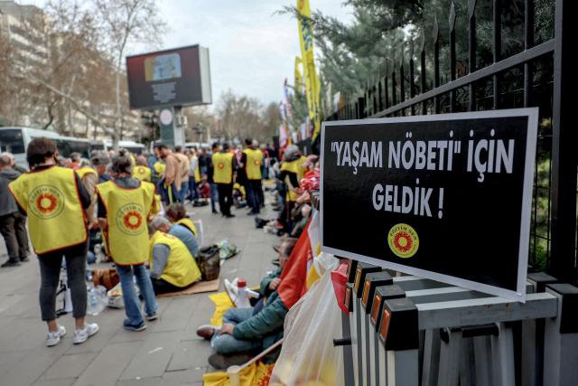 This photograph shows a placard reading "We have come for the life vigil" as members of education unions stage a sit-in to protest school shootings in front of the Ministry of National Education headquarters in Ankara, on April 15, 2026. A 13-year-old opened fire at a Turkish school on April 15, 2026, killing nine people and wounding 13, with students jumping from windows to escape the second school shooting in the country in as many days, officials said. (Photo by Adem ALTAN / AFP)