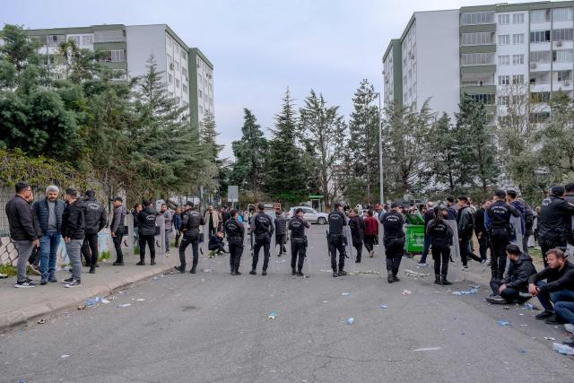 Families wait as Turkish anti riot police officers block a street near a school where a 13 year-old teenager opened fire in Kahramanmaras, on April 15, 2026. A 13-year-old opened fire at a Turkish school on April 15, 2026, killing nine people and wounding 13, with students jumping from windows to escape the second school shooting in the country in as many days, officials said. (Photo by Orhan ERKILIC / AFP)