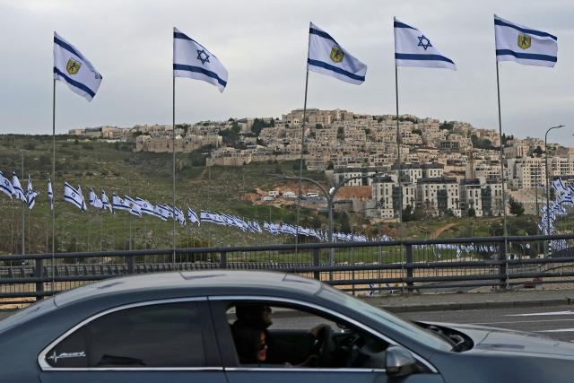 A car drives through a road installed with Israeli flags at Ramat Shlomo, a Jewish settlement in the Israeli-annexed eastern sector of Jerusalem, on April 15, 2026. (Photo by AHMAD GHARABLI / AFP)