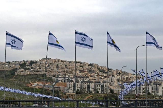 This photograph taken from the outskirts of the east Jerusalem neighbourhood of Beit Hanina, shows Israeli flags along the road at Ramat Shlomo, a Jewish settlement in the Israeli-annexed eastern sector of Jerusalem, on April 15, 2026. (Photo by AHMAD GHARABLI / AFP)