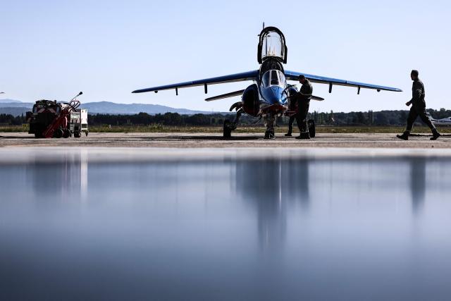 An Air Force mechanic works on an Alphajet aircraft from France's Air Force elite aerobatic flying team "Patrouille de France" (PAF) is parked in a hangar ahead of a training session at 701 Air Base in Salon-de-Provence, south-eastern France on April 15, 2026. (Photo by Thibaud MORITZ / AFP)