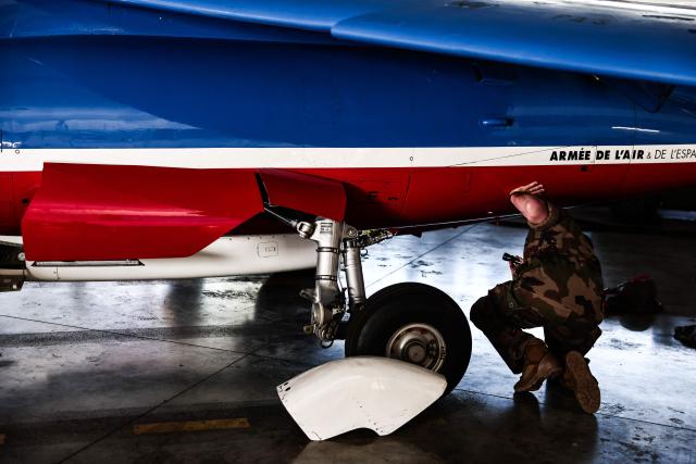 An Air Force mechanic works on an Alphajet aircraft from France's Air Force elite aerobatic flying team "Patrouille de France" (PAF) is parked in a hangar ahead of a training session at 701 Air Base in Salon-de-Provence, south-eastern France on April 15, 2026. (Photo by Thibaud MORITZ / AFP)