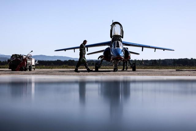 An Air Force mechanic works on an Alphajet aircraft from France's Air Force elite aerobatic flying team "Patrouille de France" (PAF) is parked in a hangar ahead of a training session at 701 Air Base in Salon-de-Provence, south-eastern France on April 15, 2026. (Photo by Thibaud MORITZ / AFP)