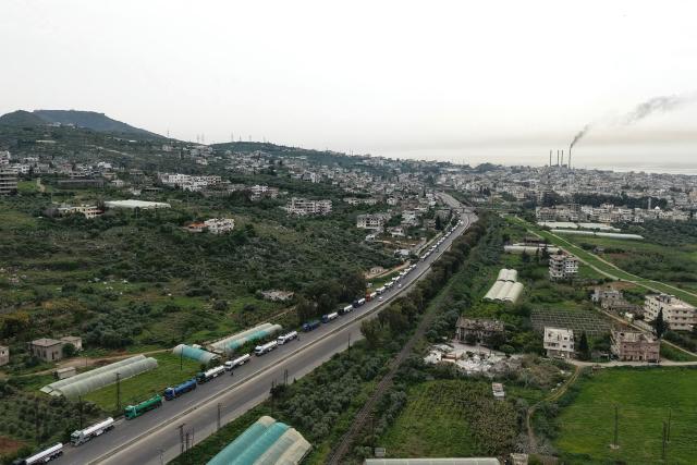 An aerial photograph shows a long line of Iraqi diesel-laden tanker trucks lined up along the Tartus-Baniyas highway as they wait to unload their cargo at the Baniyas port refinery on the Mediterranean Sea, on April 15, 2026. Iraq has begun exporting crude using tanker trucks through Syria, its oil ministry said, as an official said oil revenue last month dropped more than 70 percent compared to February. More than a month into the Middle East war that has wrought havoc on energy markets, Iraq has been particularly impacted as oil exports account for some 90 percent of its budget revenues. Until Iranian attacks and threats all but shut the Strait of Hormuz in revenge for US-Israeli strikes, Iraq exported the majority of its oil through the strategic waterway. (Photo by Bakr ALkasem / AFP)
