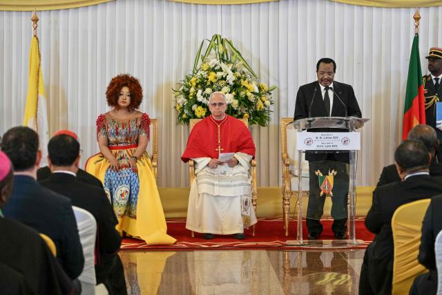 Pope Leo XIV (C) and Cameroon's First Lady Chantal Biya (L) look on as Cameroon's President Paul Biya (2nd R) delivers a speech at The Presidential Palace in Yaounde, on the third day of an 11-day apostolic journey to Africa, on April 15, 2026. (Photo by Alberto PIZZOLI / AFP)