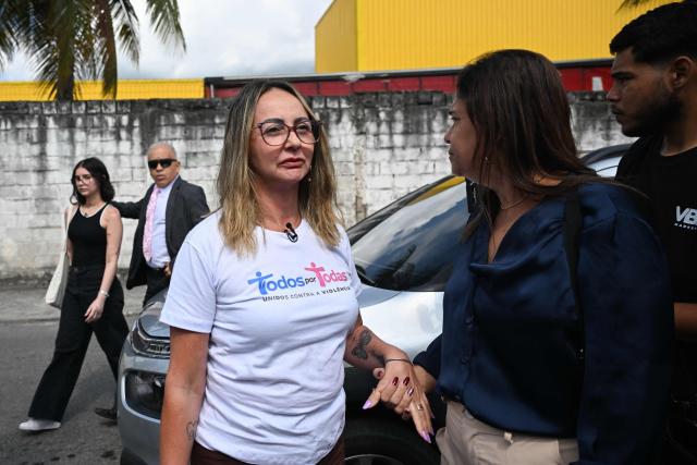 Jaderluce de Oliveira (C) and her daughter Alana Rosa (L) arrive at the Sao Goncalo Tribunal Court for the first hearing of the criminal process against Luis Felipe Sampaio, who invaded their house and tried to kill Alana, in Sao Goncalo, Rio de Janeiro state, Brazil, on April 15, 2026. Luis Felipe Sampaio stabbed Alana Rosa multiple times and was arrested accused of feminicide attempt. (Photo by Mauro PIMENTEL / AFP)