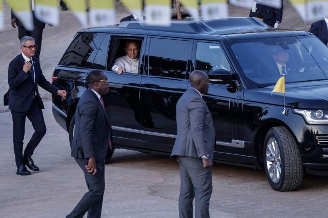 Pope Leo XIV (C) arrives in his vehicle for his visit at the Ngul Zamba (Power of God) orphanage in Yaounde, on the third day of an 11-day apostolic journey to Africa, on April 15, 2026. (Photo by Daniel BELOUMOU OLOMO / AFP) / ALTERNATE CROP