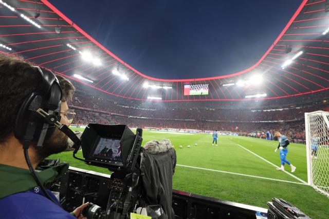 A cameraman looks at the screen of his camera from the sideline prior to the start of the UEFA Champions League quarter-final second leg football match between FC Bayern Munich and Real Madrid in Munich, southern Germany, on April 15, 2026. (Photo by Karl-Josef HILDENBRAND / AFP)