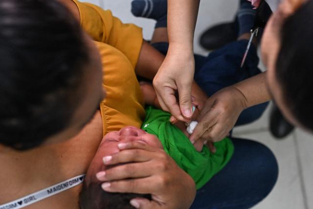 A health ministry worker vaccinates a child during a vaccination campaign against measles and other diseases at a government health center in San Salvador, on April 15, 2026. (Photo by Marvin RECINOS / AFP)