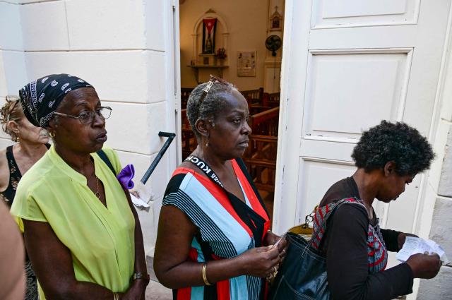 Elderly people line up to receive free medicine as social assistance at the Church of the Holy Cross of Jerusalem in Havana on April 14, 2026. Dozens of people, mainly elderly and low income persons, come to this church to receive free medicines they cannot find in pharmacies or hospitals, reflecting the social role churches are playing in a Cuba in crisis. (Photo by YAMIL LAGE / AFP)