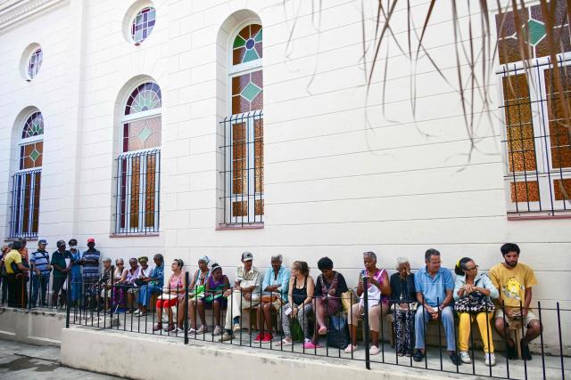 Elderly people line up to receive free medicine as social assistance at the Church of the Holy Cross of Jerusalem in Havana on April 14, 2026. Dozens of people, mainly elderly and low income persons, come to this church to receive free medicines they cannot find in pharmacies or hospitals, reflecting the social role churches are playing in a Cuba in crisis. (Photo by YAMIL LAGE / AFP)
