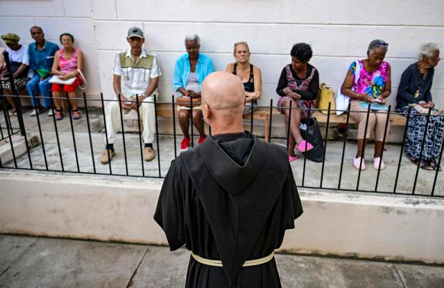Fray Luis Pernas speaks with elderly people lining up to receive free medicine as social assistance at the Church of the Holy Cross of Jerusalem in Havana on April 14, 2026. Dozens of people, mainly elderly and low income persons, come to this church to receive free medicines they cannot find in pharmacies or hospitals, reflecting the social role churches are playing in a Cuba in crisis. (Photo by YAMIL LAGE / AFP)