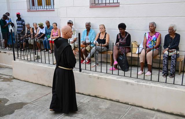 Fray Luis Pernas speaks with elderly people lining up to receive free medicine as social assistance at the Church of the Holy Cross of Jerusalem in Havana on April 14, 2026. Dozens of people, mainly elderly and low income persons, come to this church to receive free medicines they cannot find in pharmacies or hospitals, reflecting the social role churches are playing in a Cuba in crisis. (Photo by YAMIL LAGE / AFP)