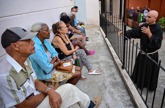 Fray Luis Pernas speaks with elderly people lining up to receive free medicine as social assistance at the Church of the Holy Cross of Jerusalem in Havana on April 14, 2026. Dozens of people, mainly elderly and low income persons, come to this church to receive free medicines they cannot find in pharmacies or hospitals, reflecting the social role churches are playing in a Cuba in crisis. (Photo by YAMIL LAGE / AFP)