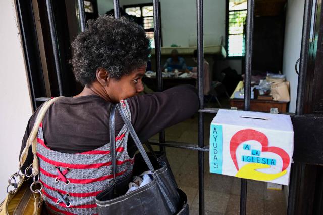 A woman waits to receive free medicines as part of a social assistance program at the Church of the Holy Cross of Jerusalem in Havana on April 14, 2026. Dozens of people, mainly elderly and low income persons, come to this church to receive free medicines they cannot find in pharmacies or hospitals, reflecting the social role churches are playing in a Cuba in crisis. (Photo by YAMIL LAGE / AFP)