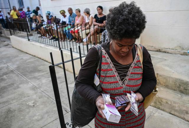 A woman leaves after receiving free medicines as part of a social assistance program at the Church of the Holy Cross of Jerusalem in Havana on April 14, 2026. Dozens of people, mainly elderly and low income persons, come to this church to receive free medicines they cannot find in pharmacies or hospitals, reflecting the social role churches are playing in a Cuba in crisis. (Photo by YAMIL LAGE / AFP)