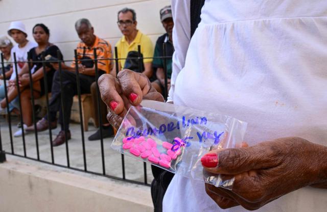 A woman leaves after receiving free medicines as part of a social assistance program at the Church of the Holy Cross of Jerusalem in Havana on April 14, 2026. Dozens of people, mainly elderly and low income persons, come to this church to receive free medicines they cannot find in pharmacies or hospitals, reflecting the social role churches are playing in a Cuba in crisis. (Photo by YAMIL LAGE / AFP)