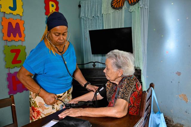 A doctor provides medical care to an elderly woman at the Nazareth Baptist Church in the neighborhood of La Vibora, in Havana, on April 14, 2026. Dozens of people, mainly elderly and low income persons, come to this church to receive free medicines they cannot find in pharmacies or hospitals, reflecting the social role churches are playing in a Cuba in crisis. (Photo by ADALBERTO ROQUE / AFP)