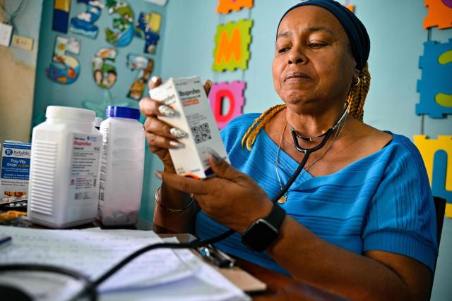 A doctor who provides medical care to elderly worshippers at the Nazareth Baptist Church, holds a medicine in the neighborhood of La Vibora, in Havana, on April 14, 2026. Dozens of people, mainly elderly and low income persons, come to this church to receive free medicines they cannot find in pharmacies or hospitals, reflecting the social role churches are playing in a Cuba in crisis. (Photo by ADALBERTO ROQUE / AFP)