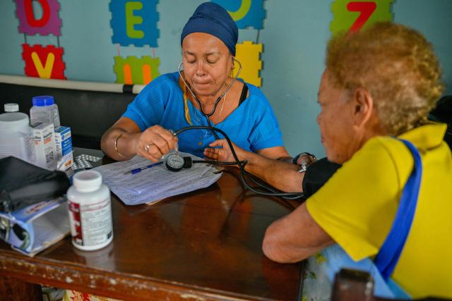 A doctor provides medical care to an elderly woman at the Nazareth Baptist Church in the neighborhood of La Vibora, in Havana, on April 14, 2026. Dozens of people, mainly elderly and low income persons, come to this church to receive free medicines they cannot find in pharmacies or hospitals, reflecting the social role churches are playing in a Cuba in crisis. (Photo by ADALBERTO ROQUE / AFP)