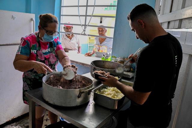 A Baptist pastor and assistants serve food to elderly worshippers at the Nazareth Baptist Church in the neighborhood of La Vibora, in Havana, on April 14, 2026. Dozens of people, mainly elderly and low income persons, come to this church to receive free medicines they cannot find in pharmacies or hospitals, reflecting the social role churches are playing in a Cuba in crisis. (Photo by ADALBERTO ROQUE / AFP)