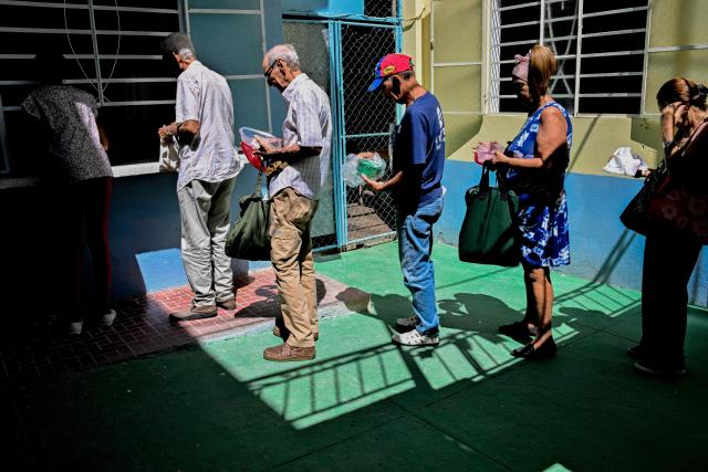 Elderly worshippers wait in line to receive a free meal at the Nazareth Baptist Church in the neighborhood of La Vibora, in Havana, on April 14, 2026. Dozens of people, mainly elderly and low income persons, come to this church to receive free medicines they cannot find in pharmacies or hospitals, reflecting the social role churches are playing in a Cuba in crisis. (Photo by ADALBERTO ROQUE / AFP)